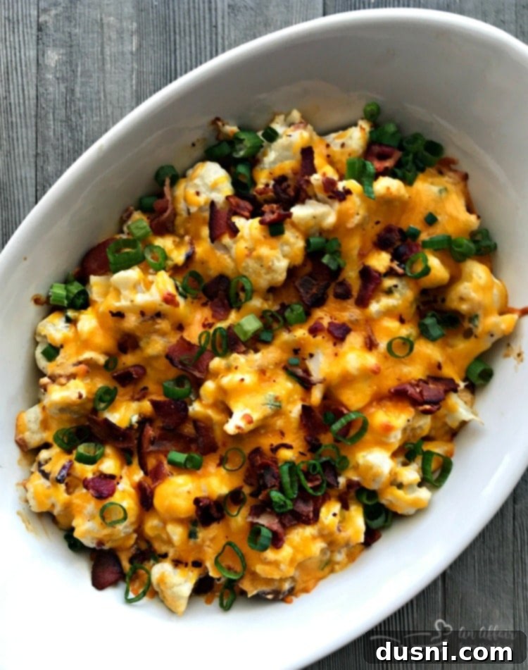 Loaded Cauliflower Casserole ready to eat in a baking dish, garnished with green onions.