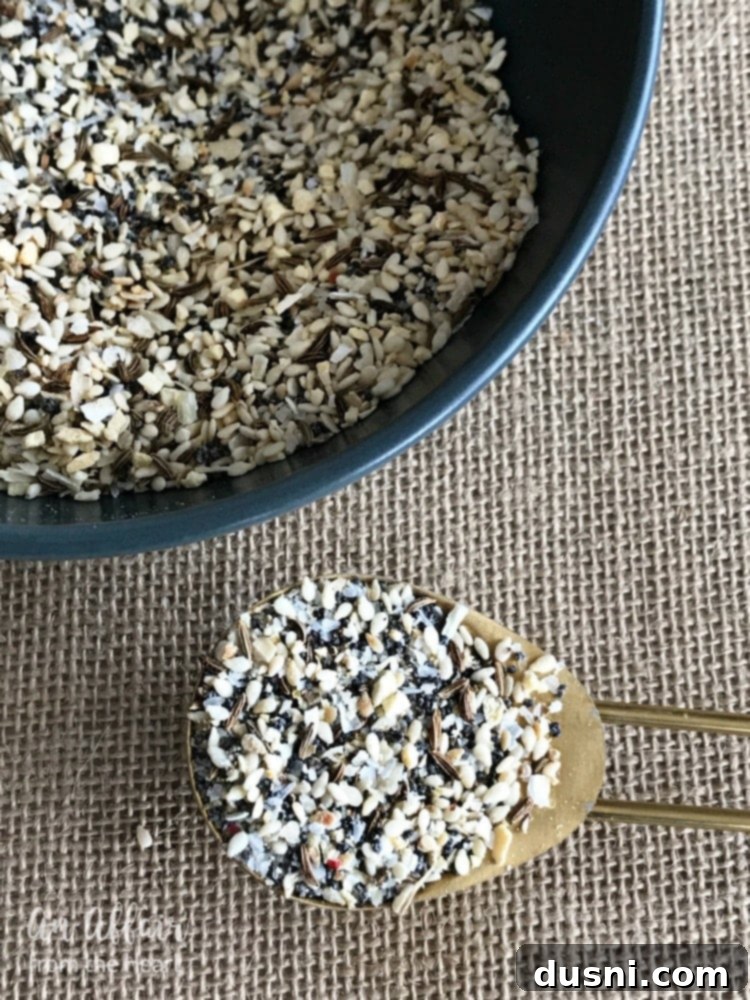 A close-up of a spoonful of Everything Bagel Spice, highlighting the various seeds and spices.