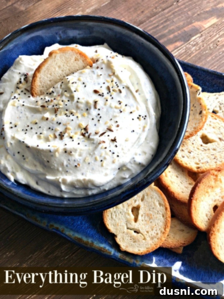 Whip Up Your Own Everything Bagel Dip 8 A stunning hero shot of the Everything Bagel Dip, generously garnished with extra everything bagel seasoning, perfectly presented in a serving bowl with fresh greens for a pop of color, ready to be enjoyed.