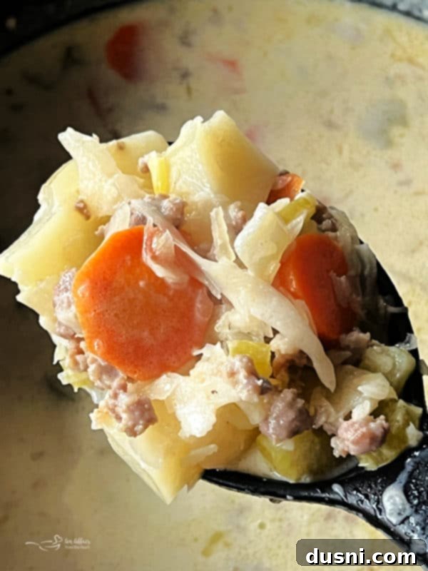 Spoonful of creamy sauerkraut soup with veggies and bratwurst