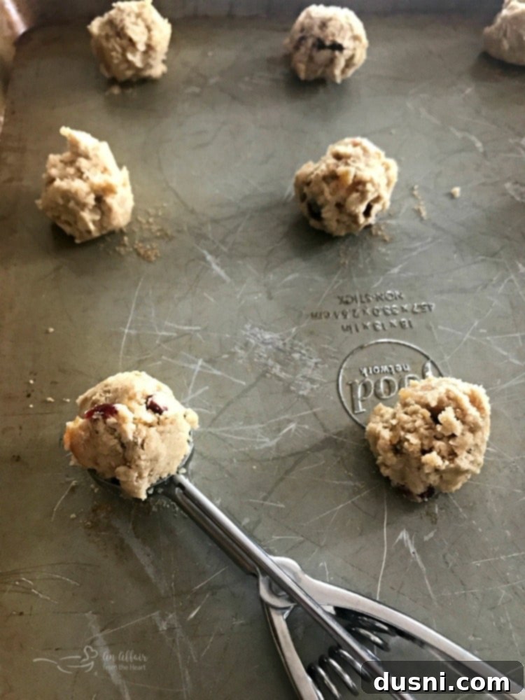 Cookie dough being scooped onto a baking sheet, ready for the oven.