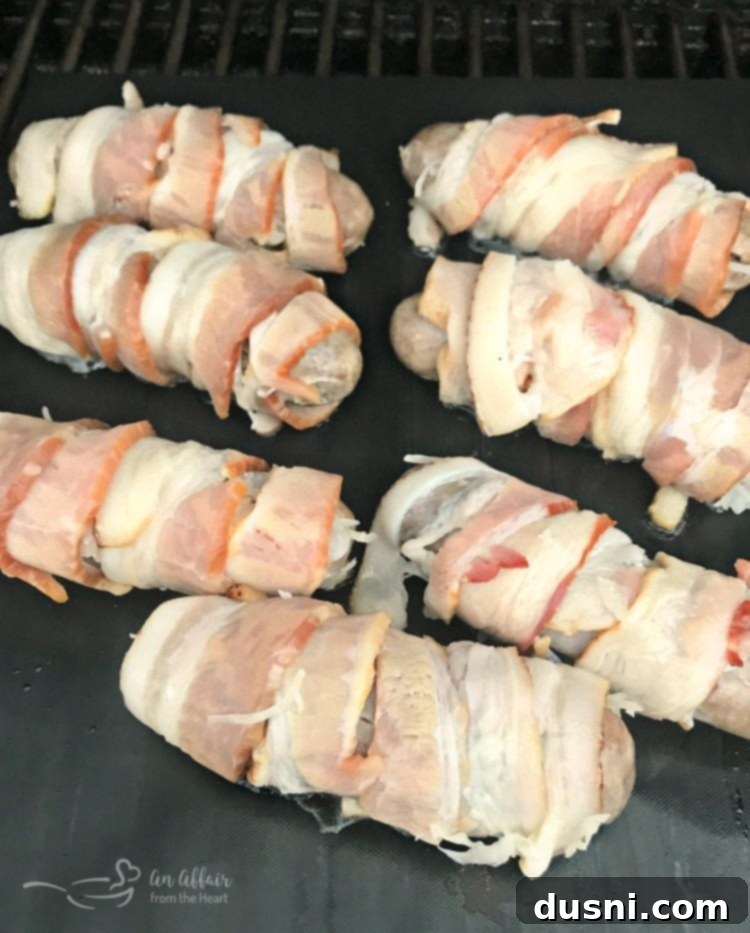 Kraut Stuffed Bacon Wrapped Brats on a grill mat, ready for grilling