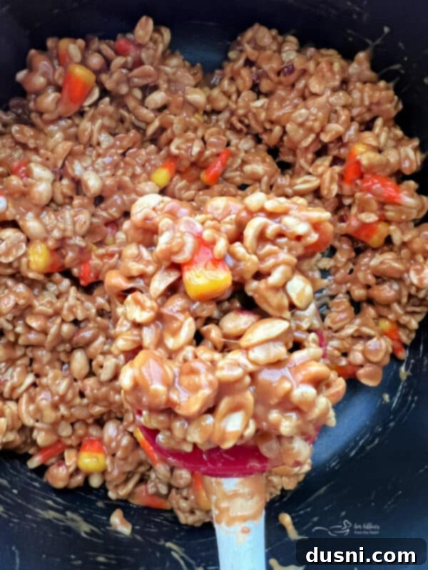 Peanut butter mixture with Rice Krispies and peanuts for Candy Corn Salted Nut Roll Bars