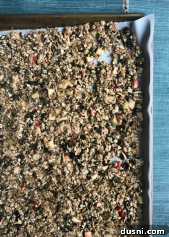 Fresh Apple Cinnamon Granola spread on a baking sheet, freshly baked