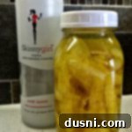 Lemon rinds and vodka in a sealed jar with a bottle of skinny girl vodka next to it