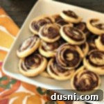 Pumpkin Spice Pie Crust Swirls 12 Close up of Pumpkin Spice Swirls - Left Over Pie Crust Cookies on a white plate, showing golden-brown edges