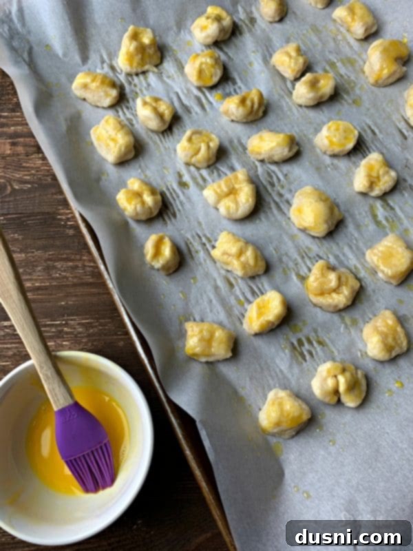 Cheesy Sauerkraut Pretzel Poppers 11 Pretzel dough balls placed on a baking sheet, brushed with egg wash and sprinkled with salt