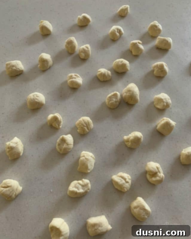Rolling small pieces of bread dough into balls for pretzel bites