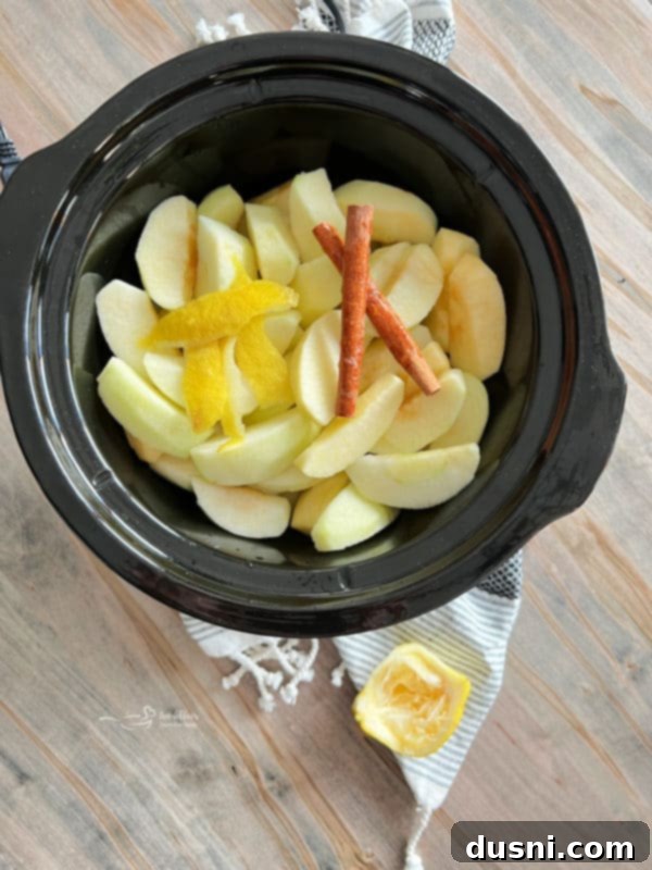 Homemade Slow Cooker Cinnamon Applesauce 5 Apples and cinnamon sticks placed in a crock pot, ready for slow cooking