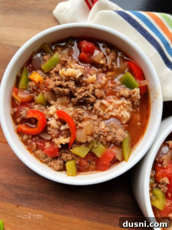 A close-up shot of Stuffed Red Pepper Soup in a rustic white bowl, highlighting the colorful ingredients.