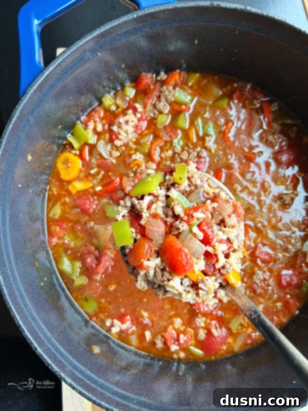 A spoon scooping a portion of Stuffed Pepper Soup, showing the rich blend of ingredients and textures.
