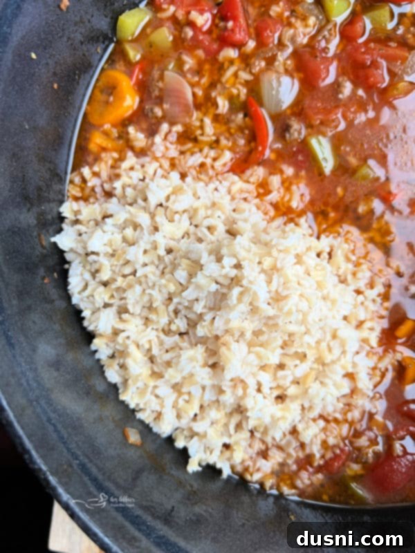 A bowl of hot Stuffed Pepper Soup, garnished and ready to be enjoyed, with a spoon resting in it.