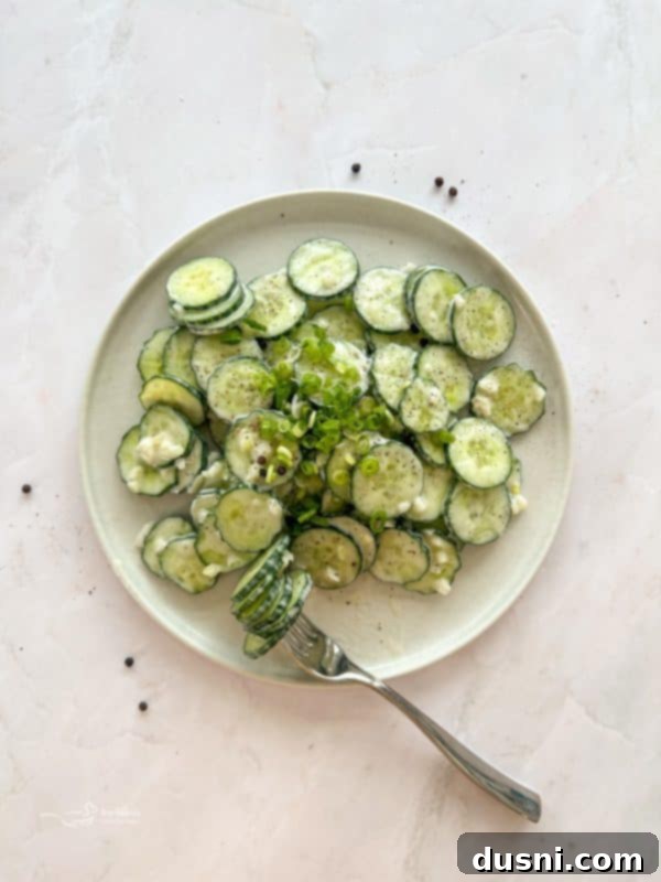 Close-up of creamy Cucumber Ranch Salad in a white bowl on a wooden surface.