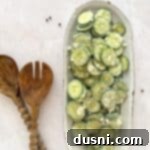 Cucumber Ranch Salad on a white serving dish and wooden salad serving spoons on a light colored table.