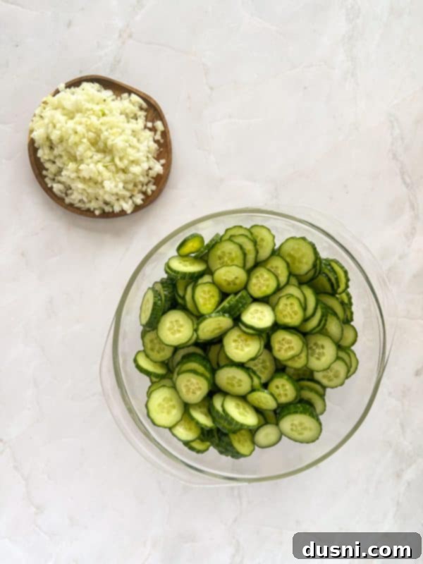 Sliced cucumbers being placed into a large bowl.