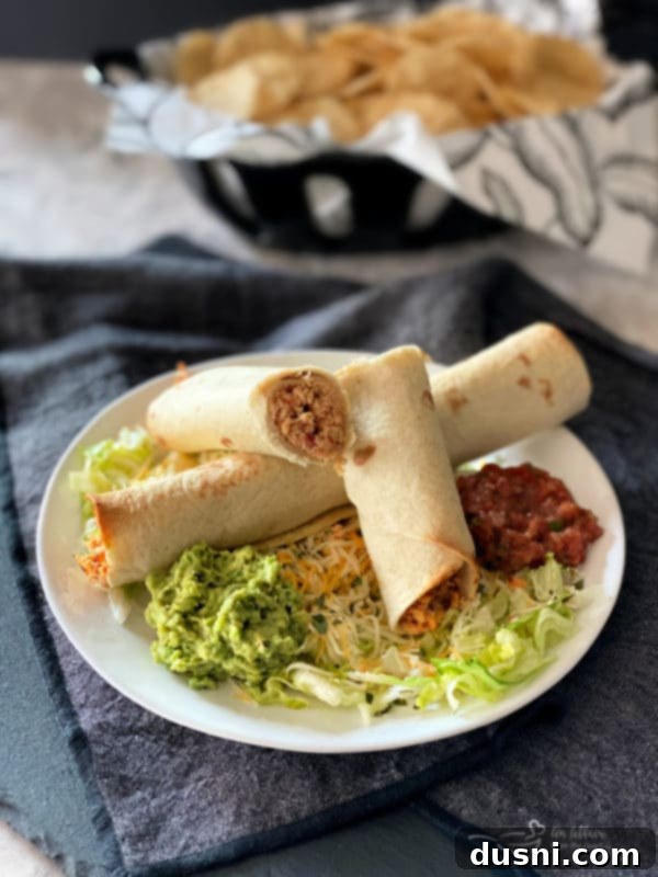 Baked Chicken Taquitos on a white plate with salsa and sour cream
