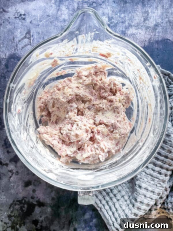 Using a hand mixer to combine Reuben Dip ingredients