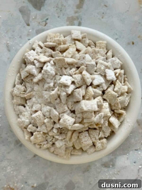 Enchanted Winter Mix 6 Close-up of white chocolate coated Chex cereal with sprinkles and powdered sugar for Winter Wonderland Snack Mix