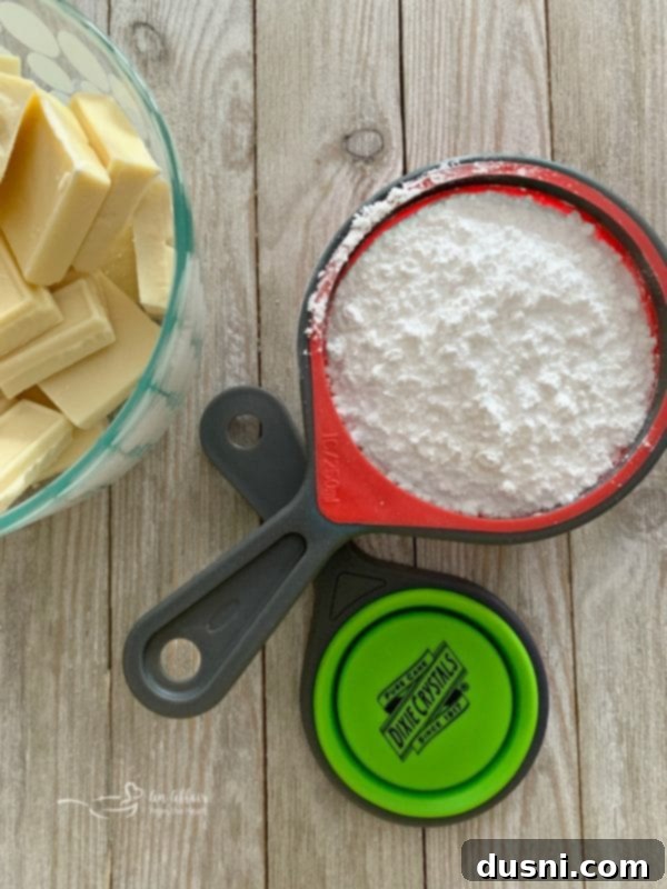 A bowl of powdered sugar and a block of cream cheese, essential ingredients for Grinch Fudge, next to a Dixie Crystals sugar bag.