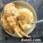 Mushroom Gravy Pork Chops 15 Pork chops with mushroom gravy, a fork and mashed potatoes on a cream color plate.