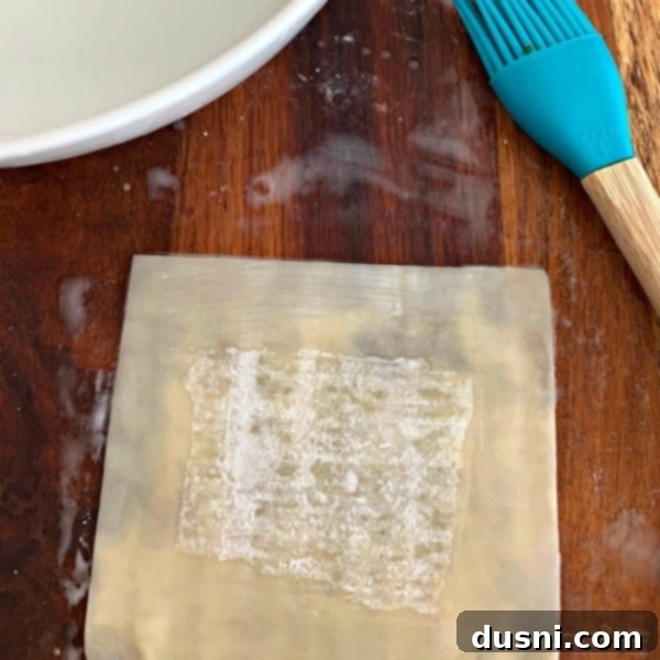 Wetting the edges of wonton wrappers with a pastry brush