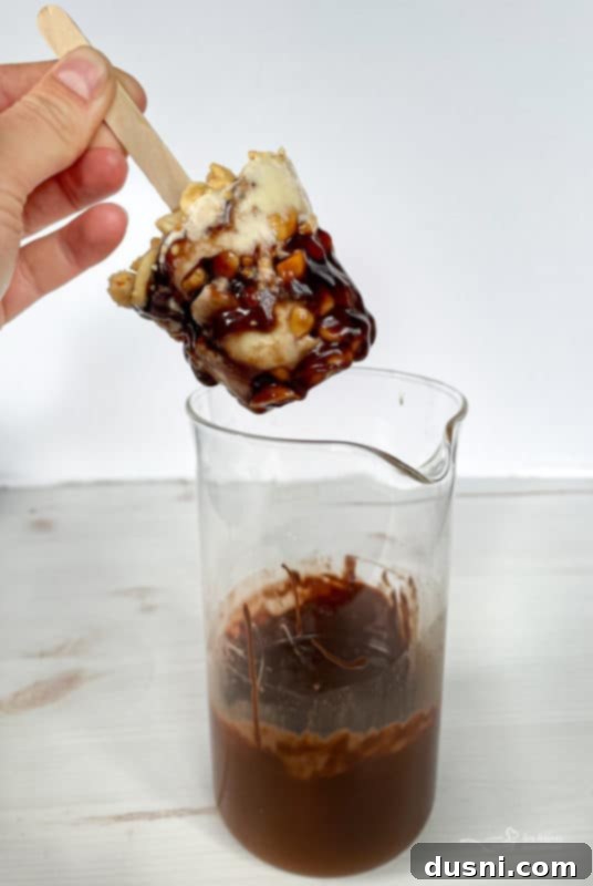 A frozen Buster Bar being dipped into melted chocolate
