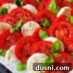 A vibrant Caprese Salad, featuring red tomatoes, white mozzarella, and green basil, ready to be served.