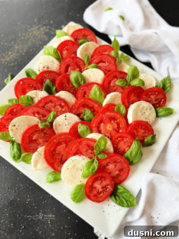 Freshly ground black pepper being sprinkled over a Caprese salad, enhancing its flavor.