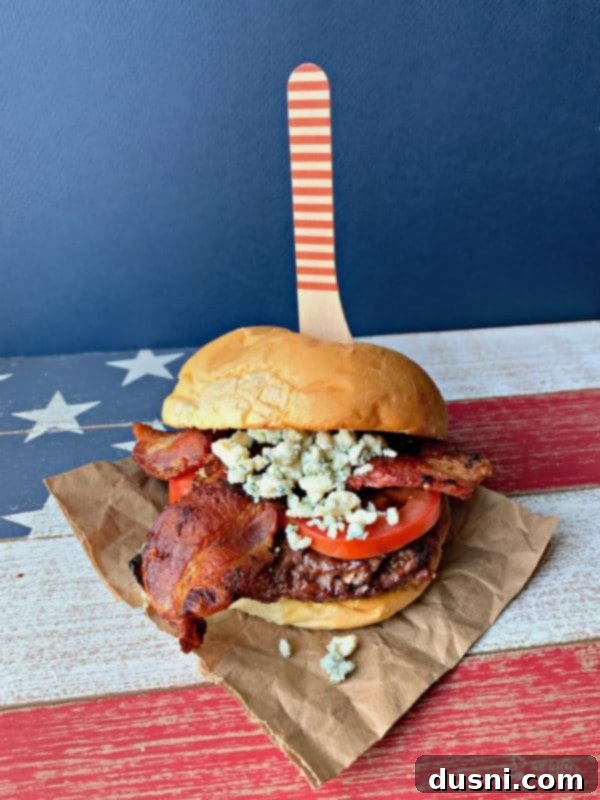 A beautifully presented Red, White & Bleu Burger, showcasing its layers of bacon, tomato, and bleu cheese on a toasted bun.