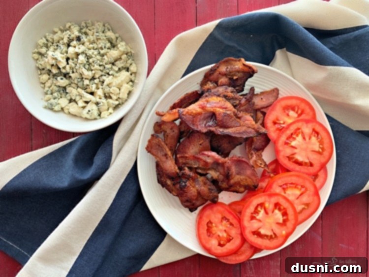 Prepped ingredients for Red, White & Bleu Burger including bacon, tomato, bleu cheese, and ground beef mixture.
