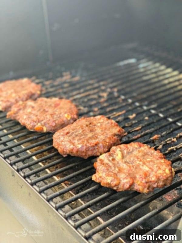 Red, White & Bleu Burgers cooking on a hot outdoor grill, showing grill marks.