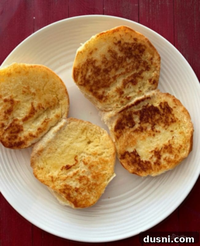 Burger buns being toasted in a hot skillet with melted butter for extra flavor and crispness.