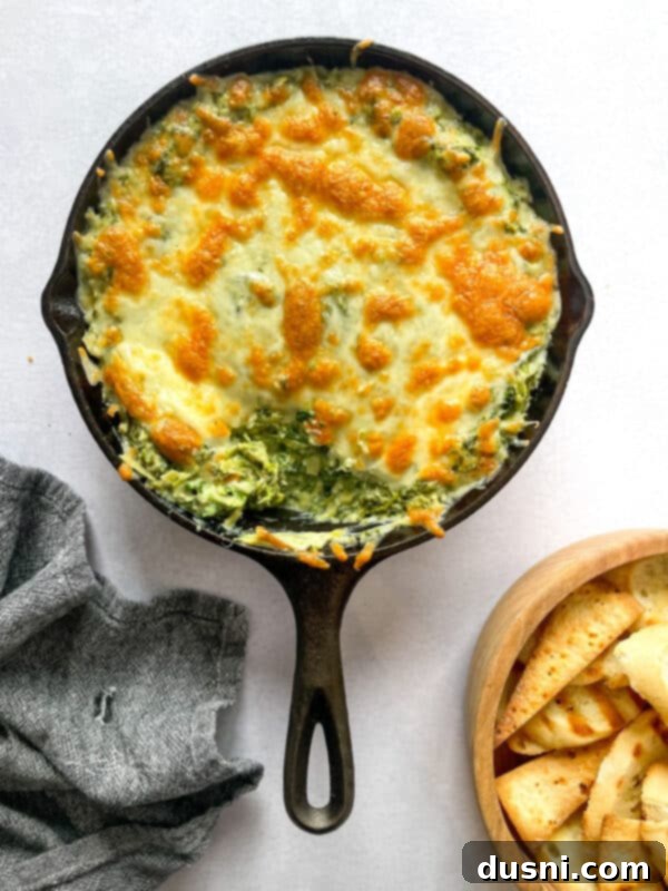A close-up shot of a warm, bubbly spinach artichoke dip in a baking dish, ready to be served.
