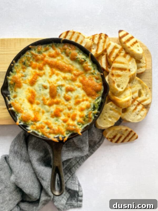 A delightful close-up of the golden-brown, bubbly spinach artichoke dip fresh from the oven, served in a cast iron skillet.