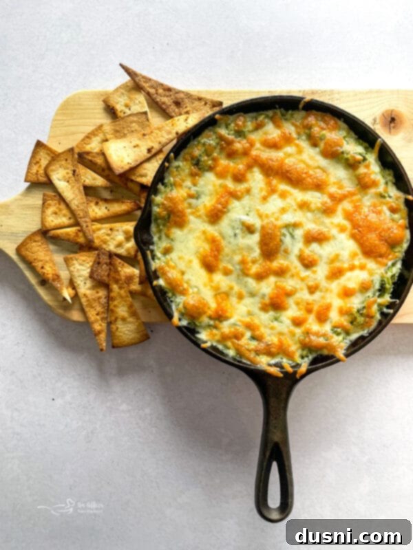 A close-up of the delicious baked spinach artichoke dip with a golden, bubbly cheese top.