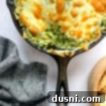 Close up of Spinach artichoke dip in a skillet surrounded by grilled bread.