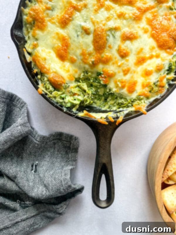 A close-up shot of the raw ingredients for spinach artichoke dip: spinach, artichokes, garlic, and cheese blend.