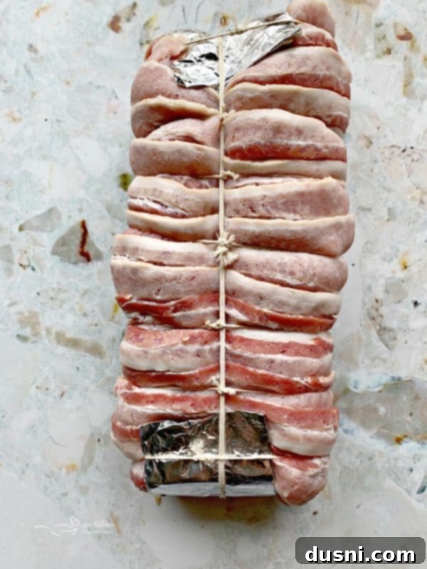 Pastırmalı Lahana Turşusu Dolgulu Domuz Kontrafile 11 Bacon-wrapped pork loin tied with butcher's twine, ready for the smoker.