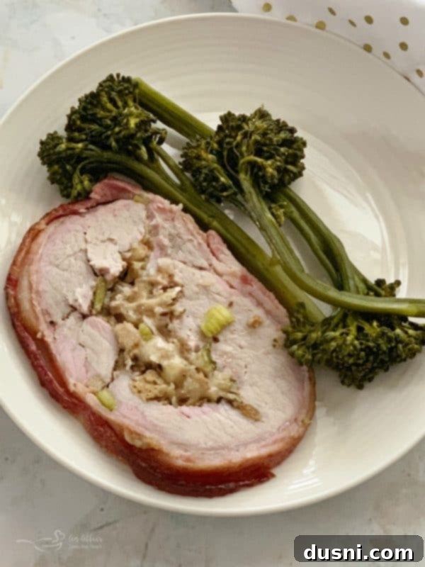 Pastırmalı Lahana Turşusu Dolgulu Domuz Kontrafile 15 Sliced bacon-wrapped pork loin with sauerkraut stuffing served on a white plate with broccolini.