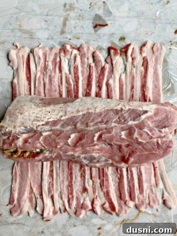 Pastırmalı Lahana Turşusu Dolgulu Domuz Kontrafile 10 Arranging bacon strips on plastic wrap to prepare for wrapping the pork loin.