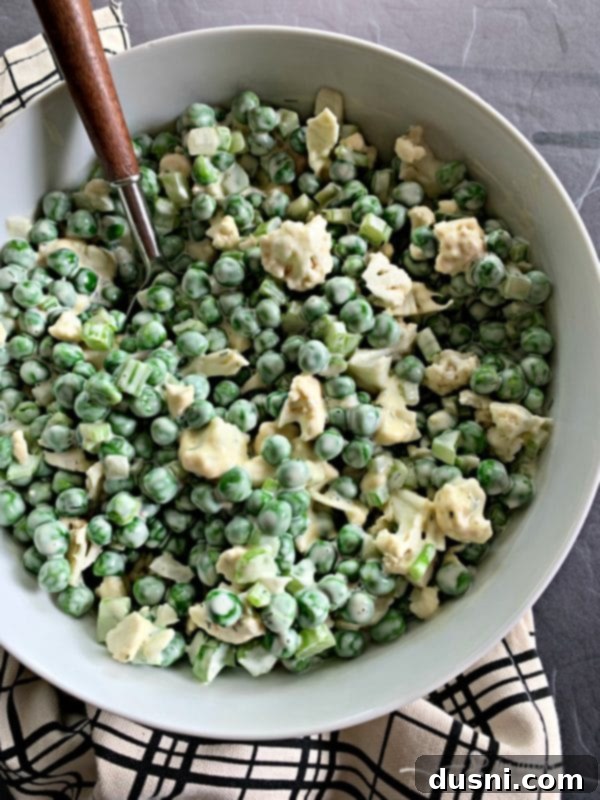 Pea Salad with Cauliflower in a white bowl, garnished with fresh dill.