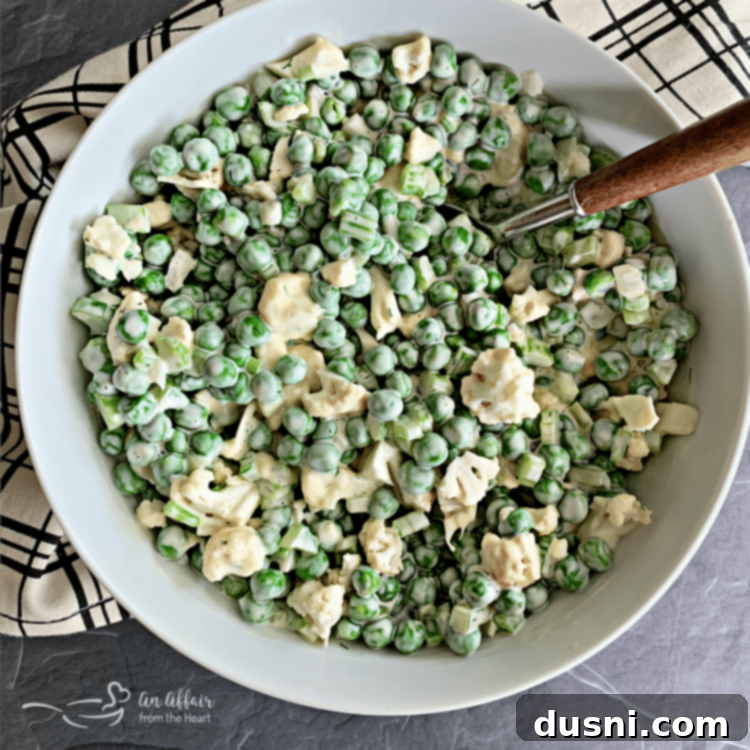 A square overhead shot of the finished Pea Salad with Cauliflower in a white serving bowl.