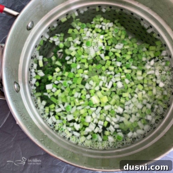 Frozen peas, chopped onion, and celery being blanched in boiling water.
