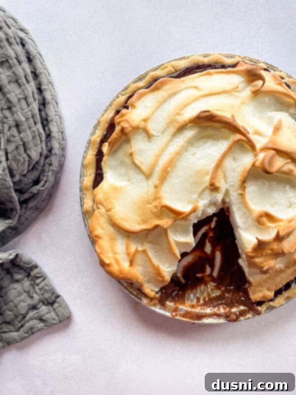 A full chocolate meringue pie, freshly baked with a golden, toasted meringue top.