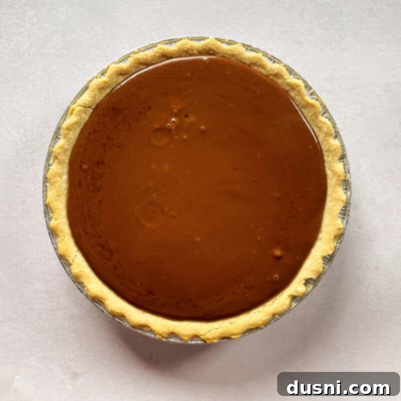 Chocolate custard being poured into a pre-baked pie crust.