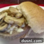 close up of burger on a white plate with text "Garlic Mushroom Burgers"