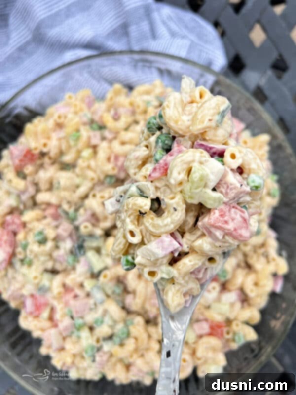 A serving of creamy Spam pasta salad in a small glass bowl, with a fork ready to dig in.