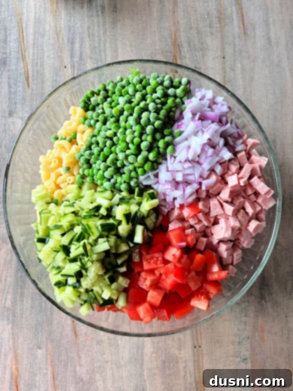 The creamy pasta salad dressing sits in a bowl, ready to be added to the other ingredients.