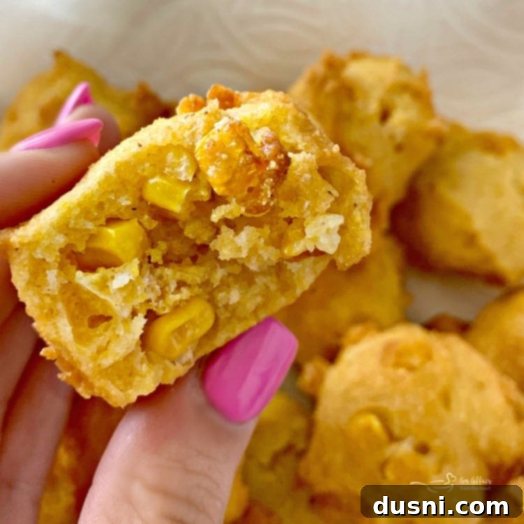 Close-up of a corn fritter cut in half, revealing the texture and sweet corn kernels inside.