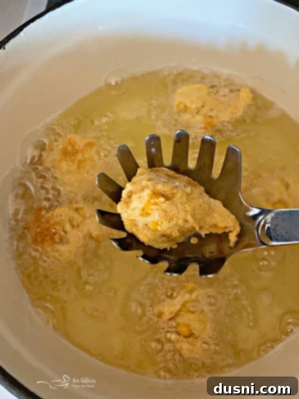 Corn fritter batter ready for frying, with a scoop and a bowl of corn.
